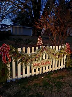 a white picket fence with christmas decorations on it and a sign that says merry christmas