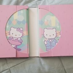 an open hello kitty book on a bed with pink sheets and polka doted background