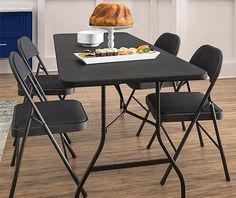 a dining table with black folding chairs and a loaf of bread on top of it