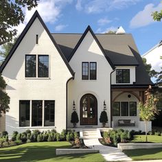 a large white house with black trim on the front and side windows is shown in this image