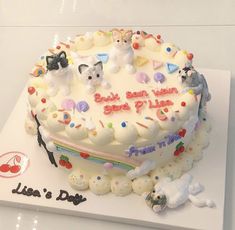 a birthday cake decorated with dogs and cats on it's side, sitting on top of a table