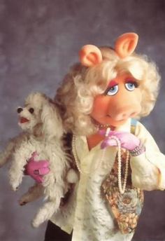 the muppet doll is holding two stuffed animals in her arms and looking at the camera