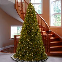 a christmas tree is in the middle of a room with stairs and lights on it