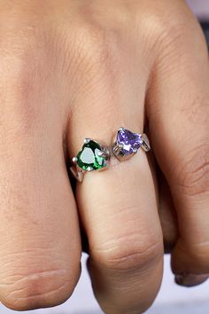 a person's hand with two rings on their fingers and one has three different colored stones