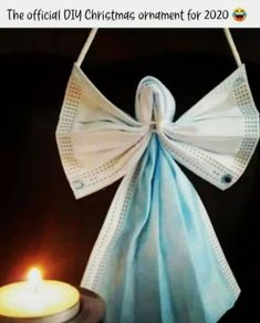 a candle that is sitting next to a cloth bag with a bow on it and a lit candle in front of it