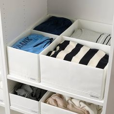 an organized closet filled with clothes and folded shirts in white bins on shelving units