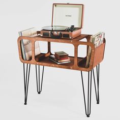 an old record player is on top of a table with hairpin legs and a record case