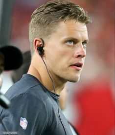 a close up of a person wearing headphones on a field with an american football team in the background