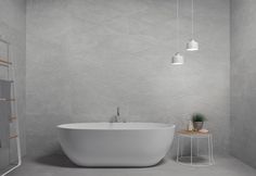 a white bath tub sitting in a bathroom next to a wooden table and light fixture