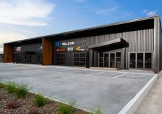 an empty parking lot in front of a building with large doors and windows on the side