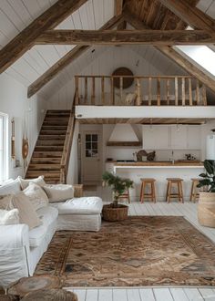 a living room filled with white furniture and wooden beams on the ceiling, next to a stair case