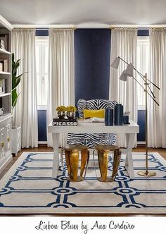 a living room with blue walls and white carpeted flooring, gold accents on the table