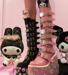 two hello kitty dolls sitting next to each other on top of pink and black shoes