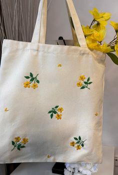 a white tote bag with yellow flowers on it