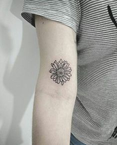 a woman's arm with a small sunflower tattoo on the left inner arm