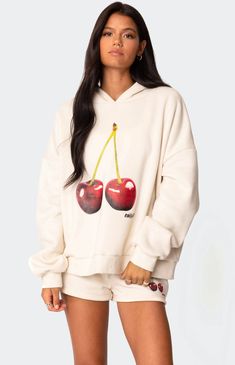 a woman wearing a white sweatshirt and shorts with cherries printed on the front,