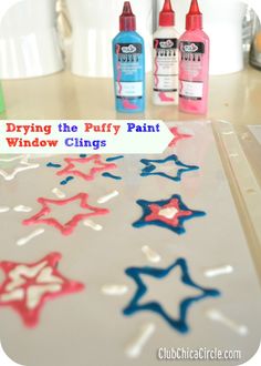 some spray paint stars on a table with other items in front of it and the words, drying the puffy paint window clings