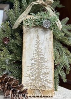 a wooden sign with pine cones on it next to a christmas tree and other decorations