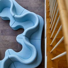 a blue couch sitting on top of a wooden floor next to a stair case with handrails