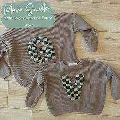 two knitted sweaters with green and white designs on them, one has the letter v