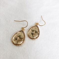 Dainty gold teardrop earrings, made with real pressed flowers preserved in crystal clear resin. These are very light weight! Great gift for nature lovers or anyone who loves minimalist jewelry. See photos for size. Because no two botanicals are identical, your item may not look exactly like the item pictured, however the same quality is guaranteed. Pendant: 24k gold plated brass Earring hooks: 24k gold plated brass GOLD FILLED EARRING HOOKS ADD ON: https://www.etsy.com/listing/840986084/gold-fil Handmade Gold Earrings For Bridesmaid Gift, Handmade Gold Earrings For Bridesmaids, Gold Pressed Flowers Dangle Earrings, Botanical Drop Earrings With Birth Flower, Botanical Birth Flower Drop Earrings, Gold Dangle Earrings With Pressed Flowers, Gold Dangle Teardrop Earrings For Bridesmaid Gift, Gold Birth Flower Drop Earrings, Gold Dangle Flower Earrings For Bridesmaids