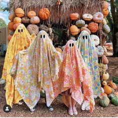 three people dressed up as ghost in front of pumpkins