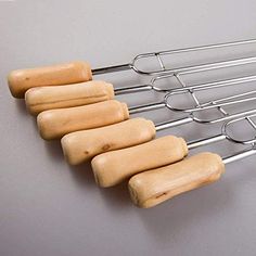 six wooden rolling pins lined up next to each other on a metal rack with wood handles