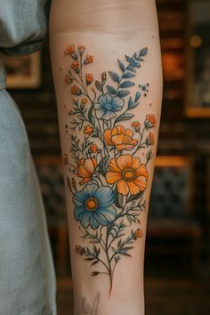 a woman's leg with an orange and blue flower tattoo on it