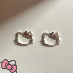 two hello kitty earrings sitting on top of a table