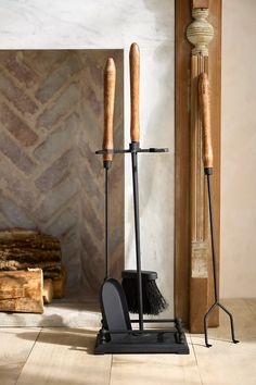 two brooms and a brush stand in front of a fireplace