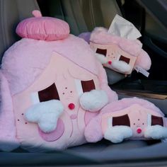 two pink pillows sitting in the back seat of a car, one is shaped like a house