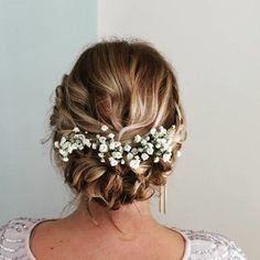 the back of a woman's head with flowers in her hair, wearing a white dress