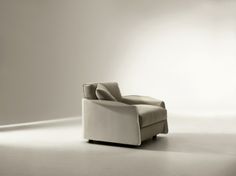 a white chair sitting on top of a floor next to a light colored wall in an empty room