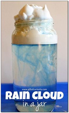 a jar filled with white and blue liquid sitting on top of a table next to the words rain cloud in a jar