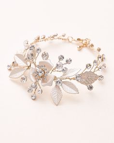 a bracelet with flowers and leaves is shown on a white surface, the bracelet has crystal stones