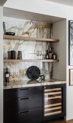 a kitchen with marble counter tops and wooden shelves filled with wine glasses on top of them