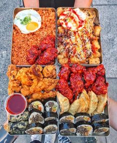 an assortment of different types of sushi and other foods in trays with dipping sauce on the side