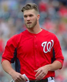 a baseball player standing on the field with his hands in his pockets and looking down