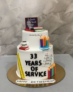 a three tiered cake decorated with books and pencils