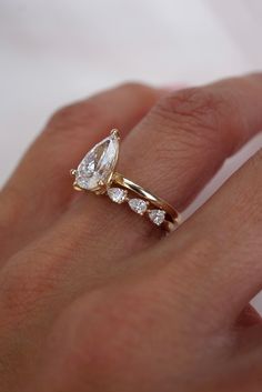 a woman's hand with a gold ring and diamond engagement ring on her finger