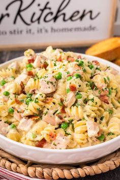 a white bowl filled with pasta and chicken on top of a table next to bread