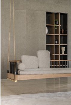 a white couch sitting on top of a wooden swing in front of a book shelf