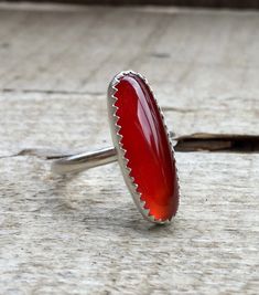 A stunning chic elongated blood red carnelian oval has been set in sterling silver with handmade ring band from sterling silver half dome wire. This stone is 22mm x 8mm in size with a simple and minimalist setting that is a serrated bezel adding a unique touch to the ring. Perfect for any boho rocker chic individual. Made to order! Carnelian is the zodiac birthstone for the signs of Leo and Virgo. Minimalist Red Oval Jewelry, Oval Carnelian Jewelry With Polished Finish, Handmade Oval Carnelian Ring, Polished Oval Carnelian Jewelry, Oval Red Carnelian Jewelry, Carnelian Ring Silver, Silver Carnelian Gemstone Rings, Silver Carnelian Ring, Boho Rocker Chic