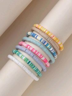 a stack of multicolored bracelets on top of a white pole next to a wall