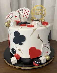 a birthday cake decorated with playing cards, dice and casino chips on a wooden table