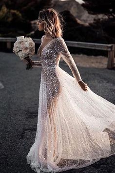 a woman in a wedding dress is walking down the road with her bouquet on her hand