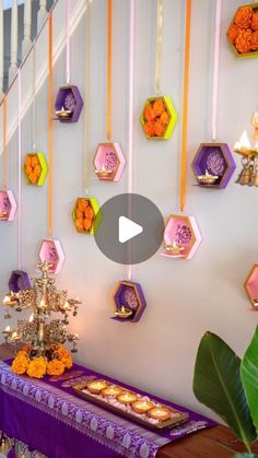 a purple table topped with lots of food next to a wall covered in hexagonal decorations