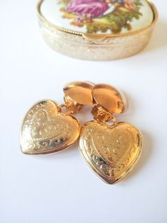 "🌹Lovely vintage gold heart earrings from a 90s deadstock, never worn and in excellent condition. These gold heart drop earrings are carved, shiny puffy drop hearts, made of resin with a brass clip on closure made with a good quality gold tone plate. They are quite lighweight. (See measurements and weight below). I offer a matching necklace on this listing: https://bit.ly/heartchainnecklace . Adding it to your order won't add shipping costs and will add a discount. MEASUREMENTS: 📏Heart length: Valentines Gift For Girlfriend, Gold Heart Earrings, Heart Clip, Gold Heart Earring, Valentine Gifts For Girlfriend, Photo Locket Necklace, Jeweled Earrings, Earrings Heart, Gold Clips