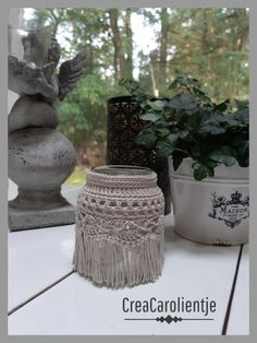 a white vase sitting on top of a wooden table next to a potted plant