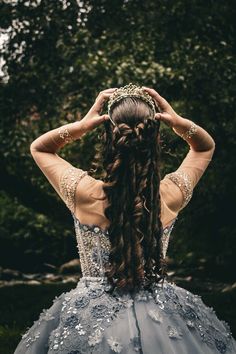 a woman with long hair wearing a blue dress and holding her hands to her head